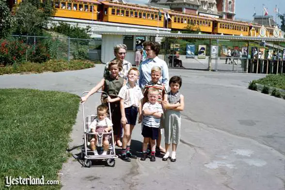 A family poses outside of Disneyland with the Passenger Train in the background